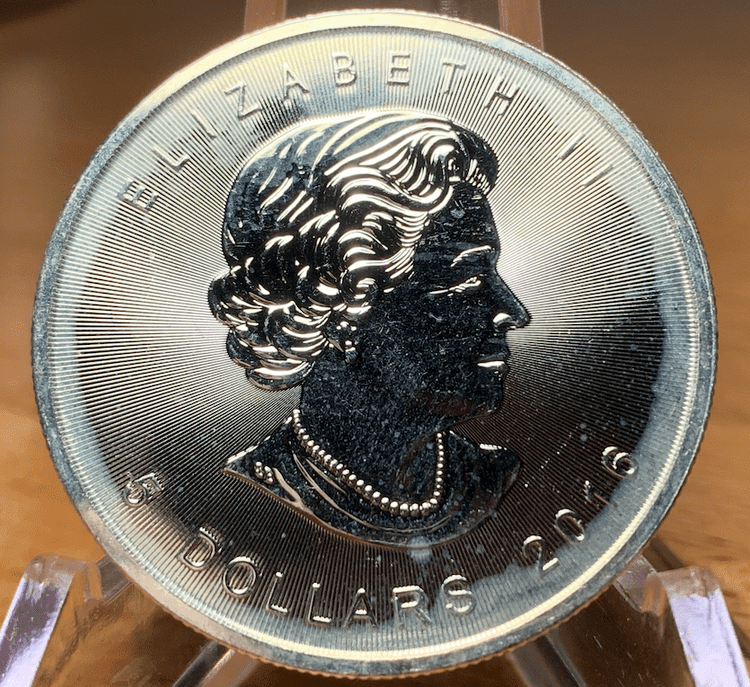 The obverse of a 2016 silver maple leaf coin covered in milk spots.